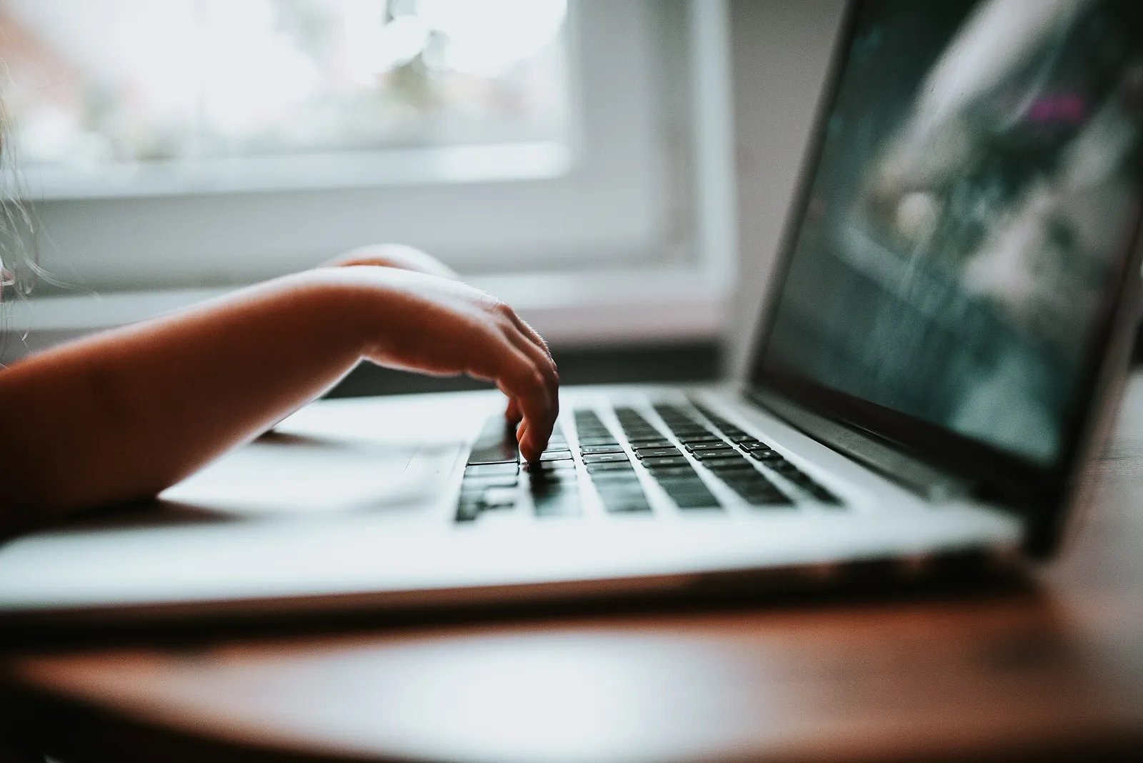 Tangan anak mengetik di papan ketik laptop